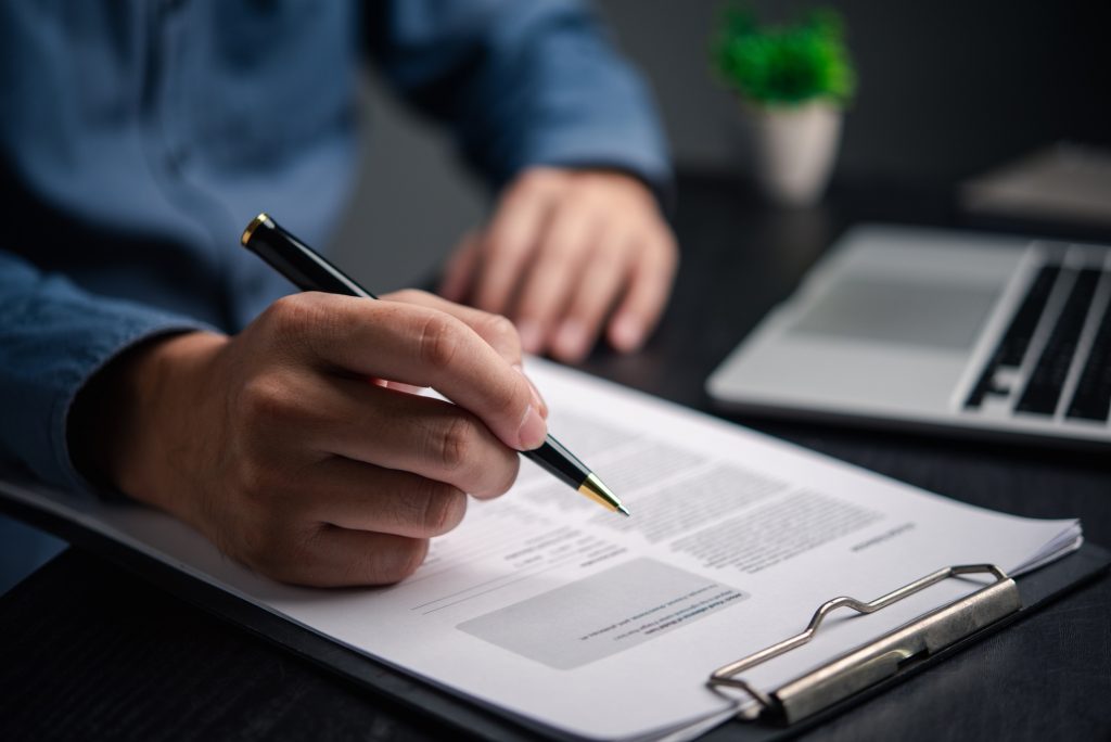 Businessman holding pen writing document plan or signature paperwork law